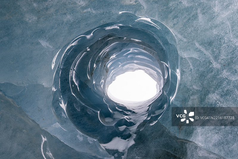 外部光线透过瑞士莫特拉茨冰川冰洞的孔洞进入。图片素材