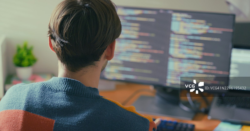 一位专注的程序员在多台电脑屏幕前工作，沉浸在编写代码中。图片素材