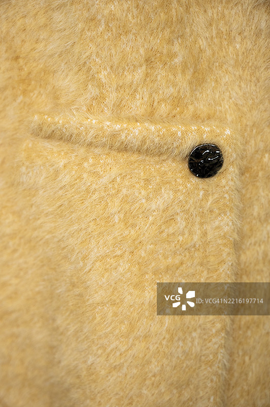 特写镜头：一件棕色夹克，扣子上有一颗黑色宝石。图片素材