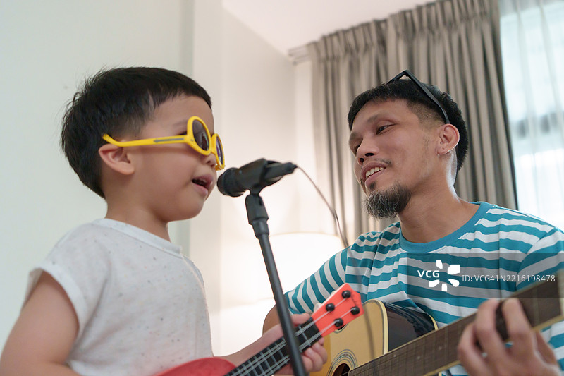 亚洲父子在客厅里一起演奏音乐，共享快乐时光图片素材