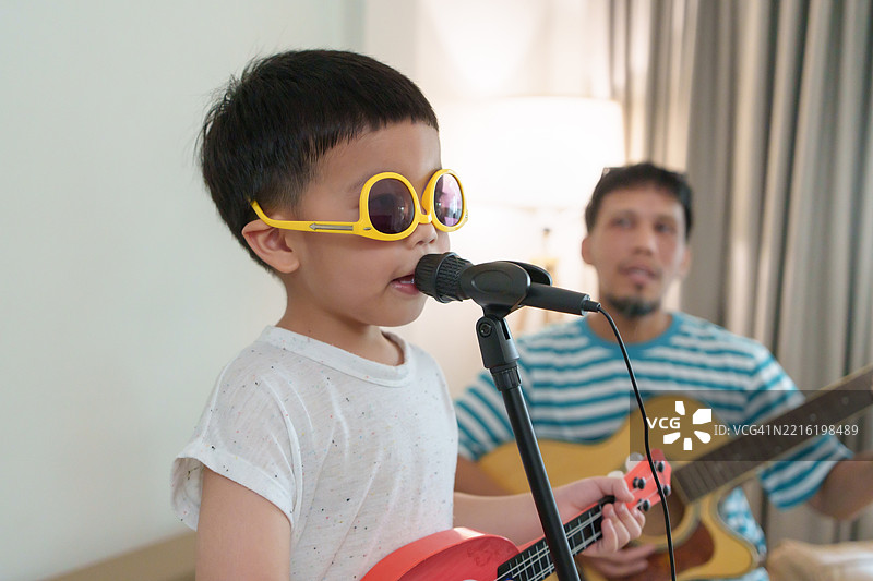 亚洲父子一起用木吉他和麦克风演奏音乐图片素材