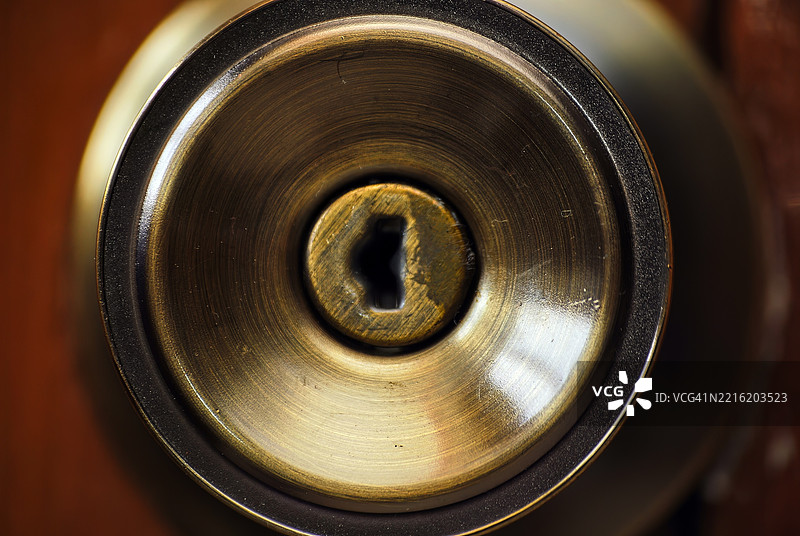 一个铜色的圆形门把手，中间有一个钥匙孔。图片素材