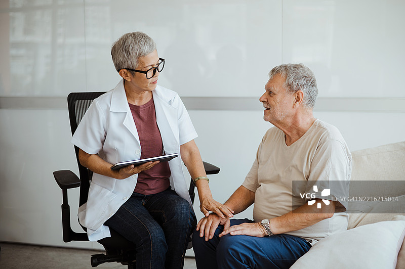 临终关怀护士探访一位年长男性患者并给予安慰。图片素材