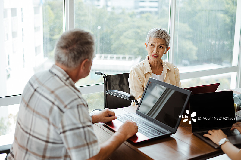 自信的老年专业人士在办公室会议中使用轮椅图片素材