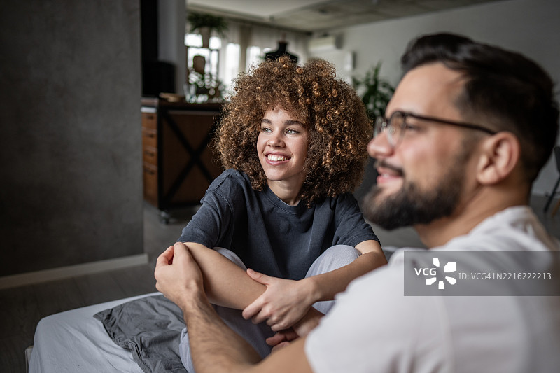 年轻情侣在现代公寓的床上放松聊天图片素材