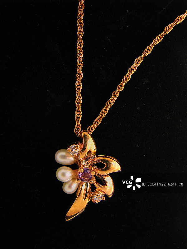 一款金镀的吊坠，配有精致的扭绳链。图片素材