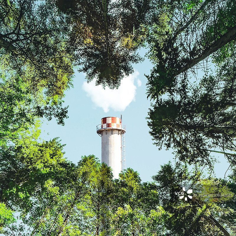 绿色洗涤概念，工业烟囱排放蒸汽与郁郁葱葱的森林形成对比图片素材