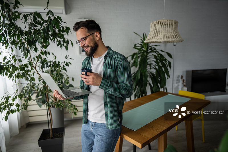 在家工作的自由职业者，享受着一杯咖啡并使用笔记本电脑图片素材