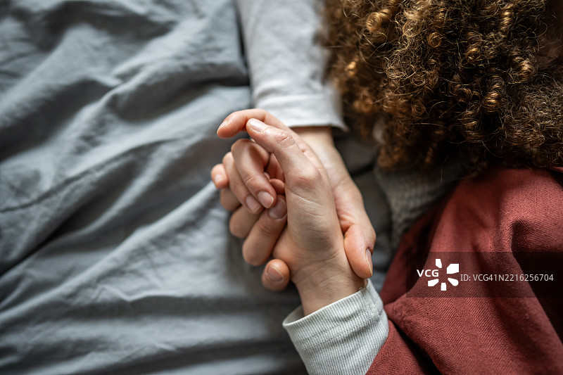 情侣在床上牵手，展现支持与爱意图片素材