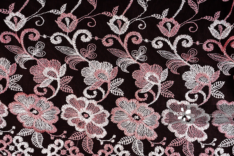 优雅的粉色花卉图案蕾丝与黑色面料衬里。图片素材