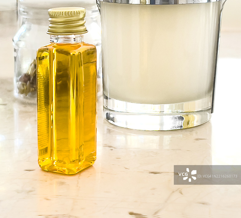 一瓶黄色洗发水放在大理石台面上，背景有一些浴室用品。图片素材