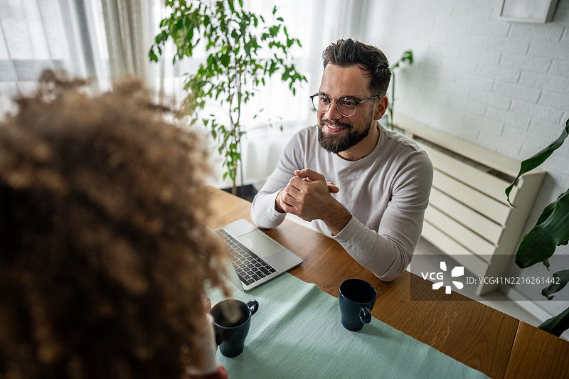 年轻男子在家中微笑着与伴侣交谈图片素材