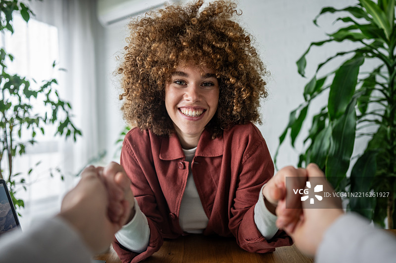 年轻女性面带灿烂笑容伸出手来打招呼。图片素材