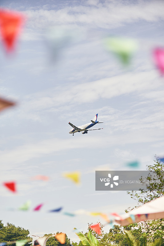 飞机在风景如画的户外环境中飞过五彩缤纷的彩旗图片素材
