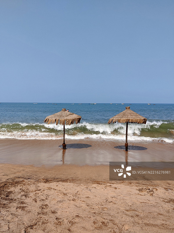 美丽的安朱纳海滩，海浪、沙滩、蓝天和圆形稻草海滩伞/帕纳吉/果阿图片素材