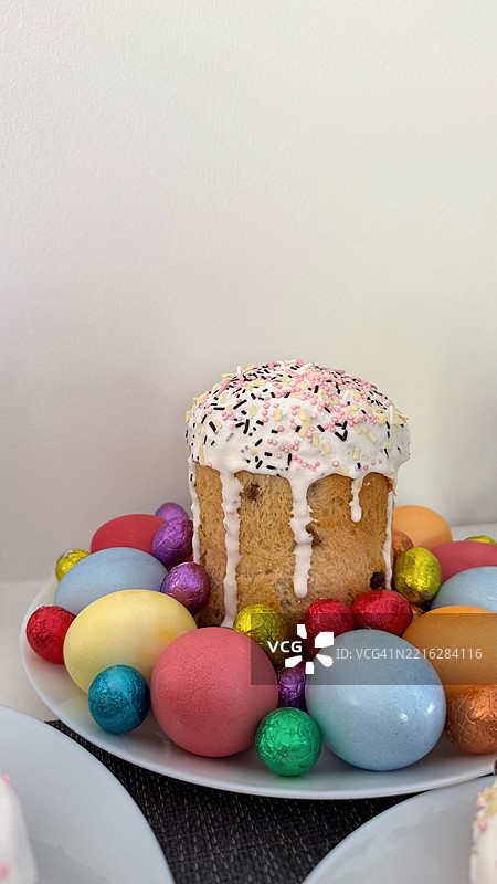 节日复活节蛋糕装饰着五彩缤纷的糖屑，周围环绕着鲜艳的彩蛋图片素材