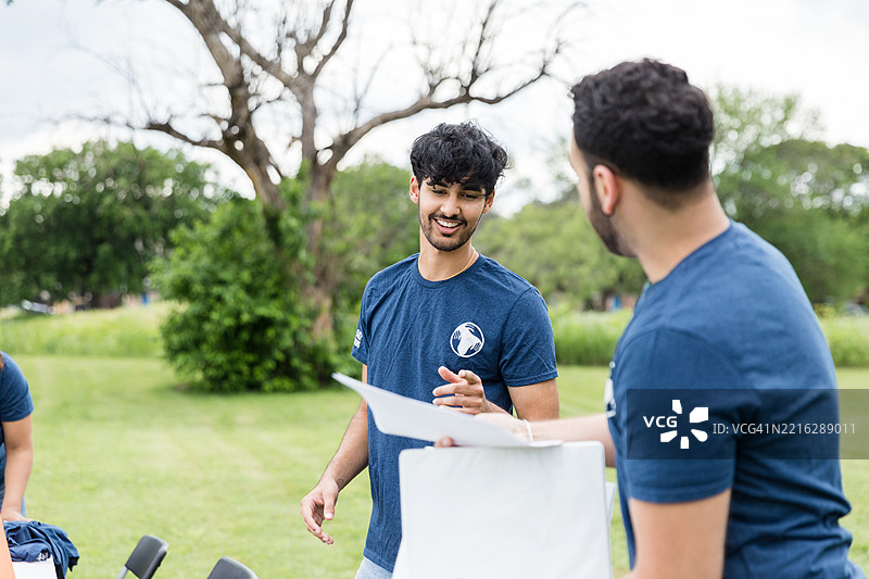 两个微笑的年轻人在户外交谈，阳光明媚的日子图片素材