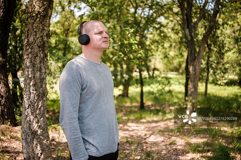 男人在大自然中享受音乐，佩戴无线耳机图片素材