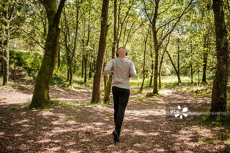 在森林中跑步的男人，戴着耳机听音乐图片素材