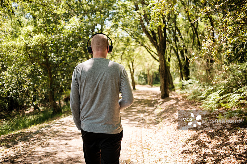 在森林中走路的男人，戴着耳机听音乐图片素材