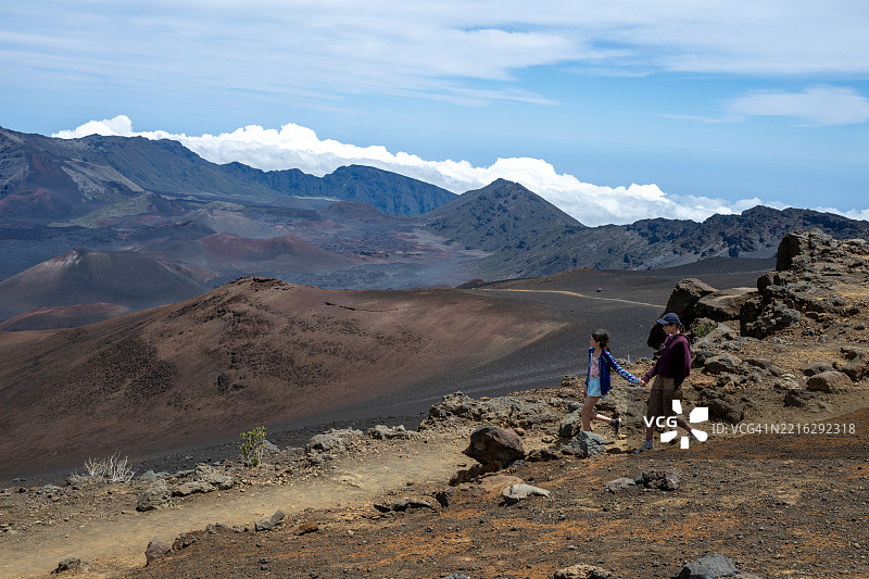 年轻女孩在哈雷阿卡拉国家公园的火山小径上徒步旅行图片素材
