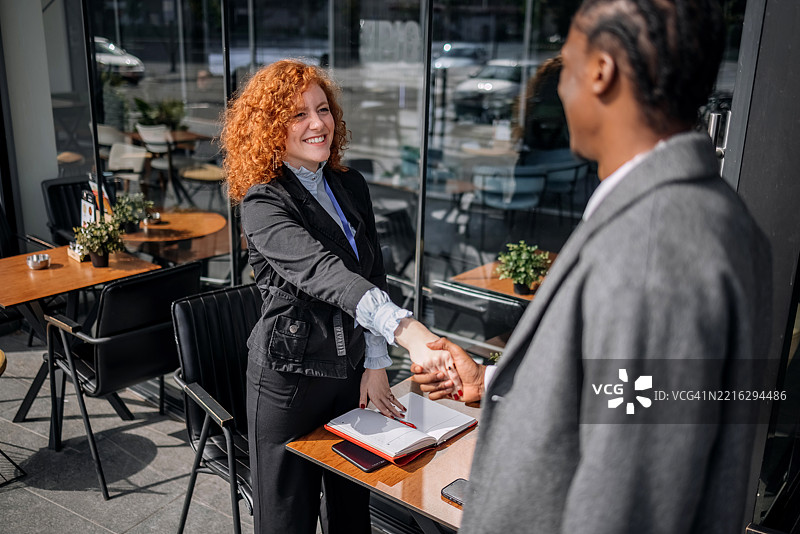 女商人与客户在咖啡馆会面并握手图片素材