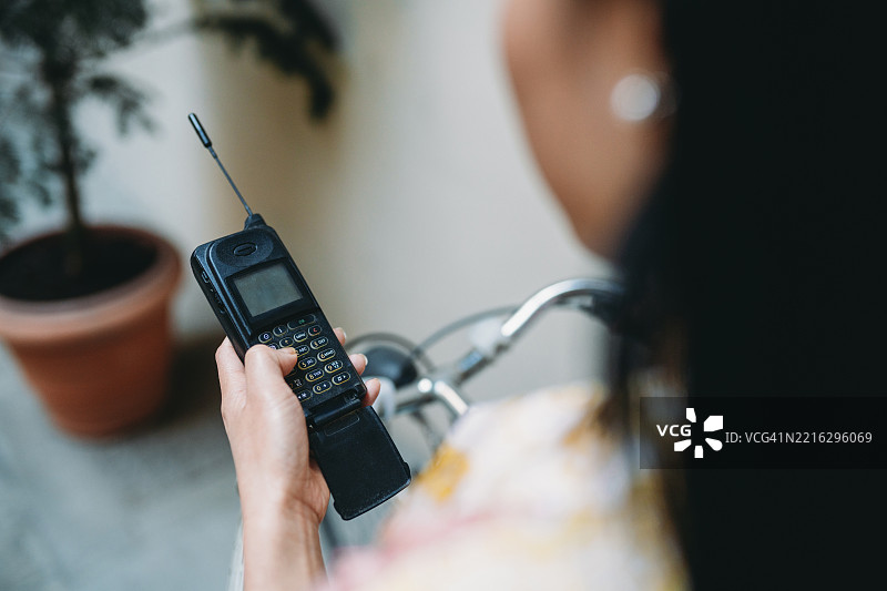 一位女性在复古手机上拨打号码，旁边有一辆自行车。图片素材