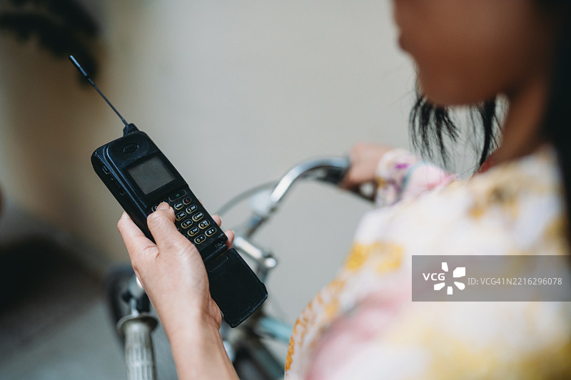 一位女性在骑自行车时拨打复古手机上的号码图片素材