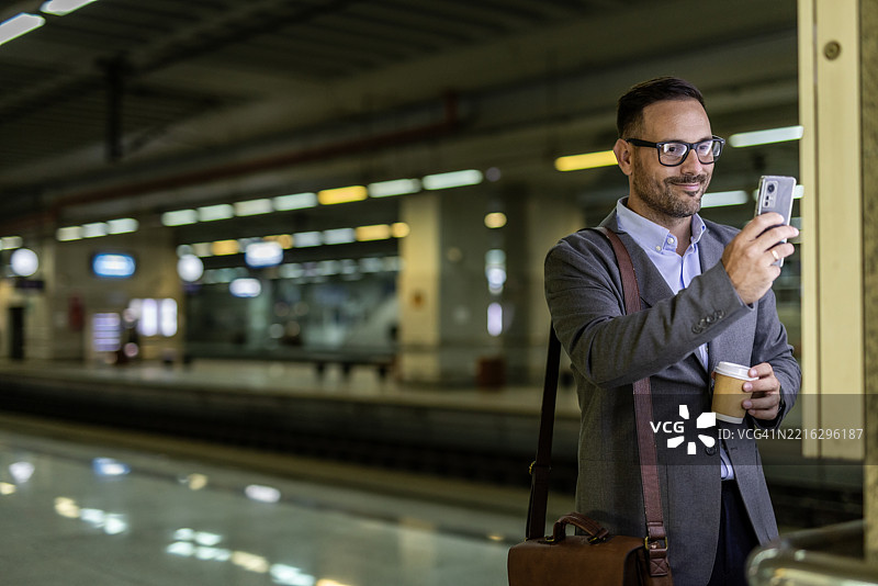 商人在火车站用智能手机拍照图片素材