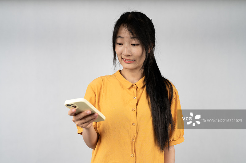 穿着黄色衬衫的女性使用智能手机图片素材