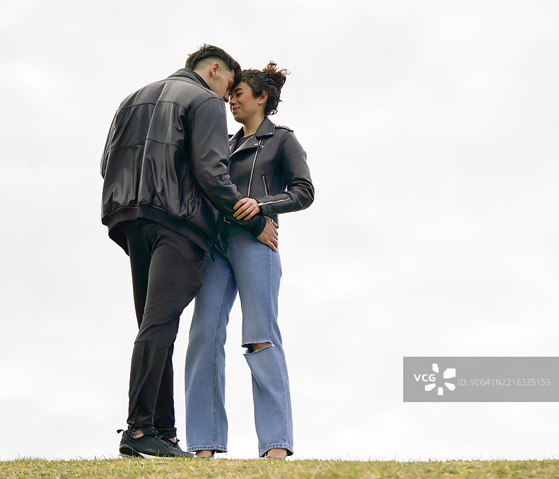 年轻情侣在户外温柔相拥，分享爱的瞬间和亲密感。图片素材