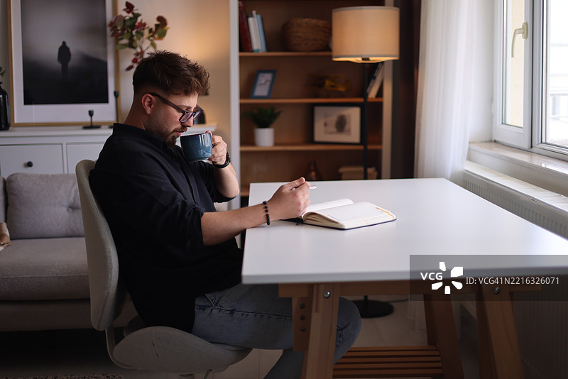 男人在桌子上写笔记本图片素材