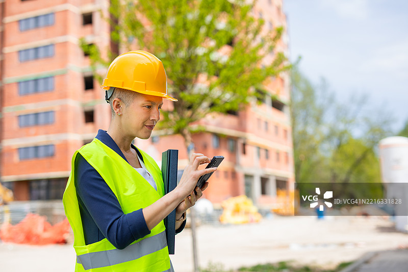 女性主管在建筑工地前使用手机图片素材
