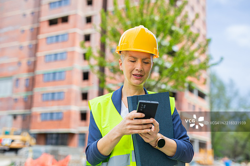 女性主管在建筑工地前使用手机图片素材