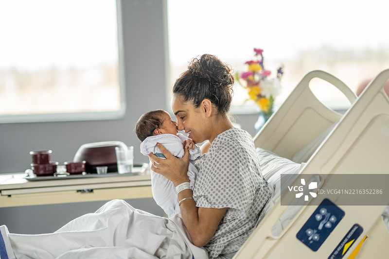 温柔的母亲在医院房间里抱着她的新生儿图片素材