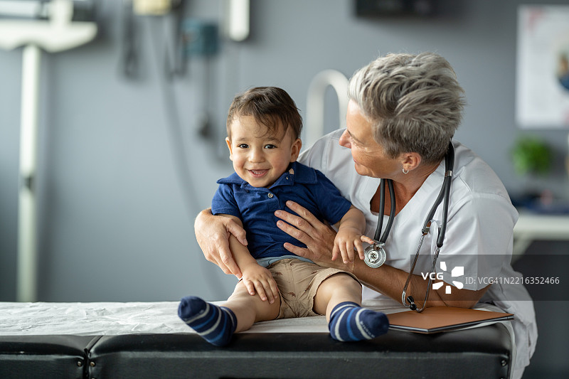 微笑的幼儿与善良的医生在医疗办公室进行儿科检查图片素材