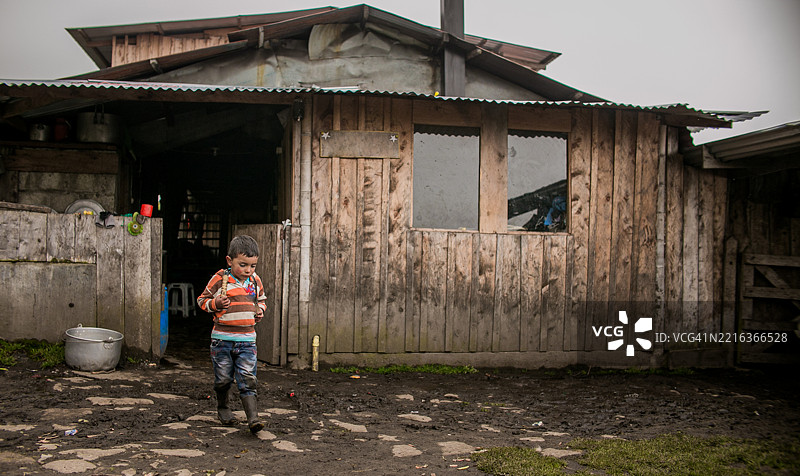 男孩在乡村山区的木屋前走。图片素材
