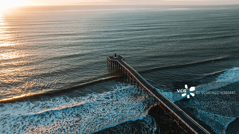 日落时分水晶码头的鸟瞰图，海浪拍打岸边图片素材