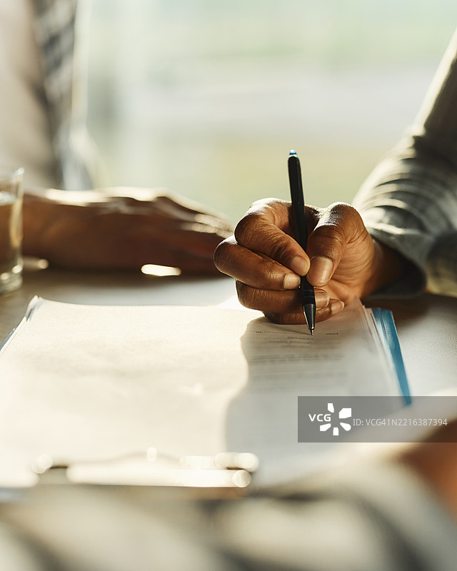 一位无法辨认的黑人正在签署合同的特写镜头。图片素材