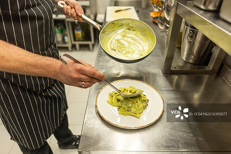 年轻厨师在餐厅厨房准备意大利面图片素材