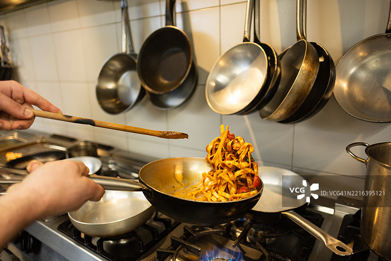 年轻厨师在餐厅厨房准备意大利面图片素材