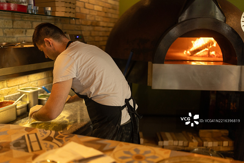 男子在比萨店里揉制比萨面团图片素材