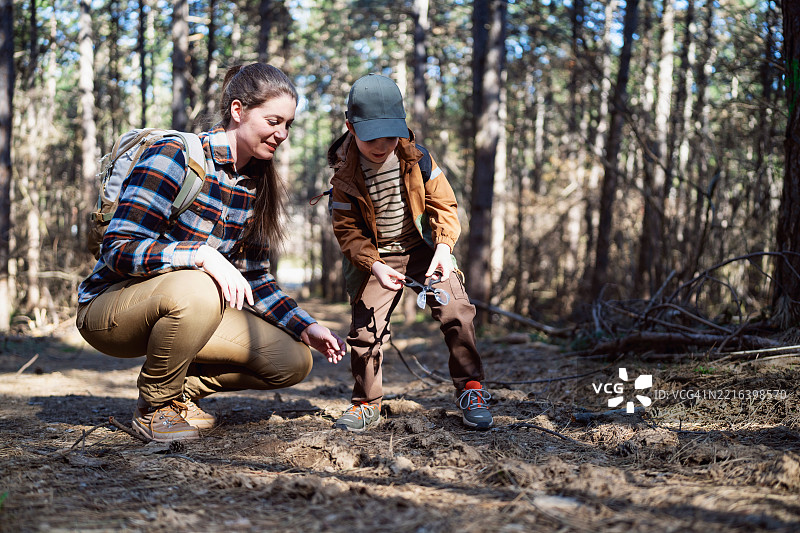 母亲和儿子一起探索森林，学习自然知识。图片素材