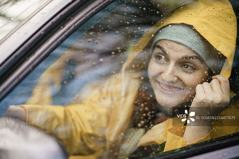 穿雨衣的快乐女人在雨天开车图片素材