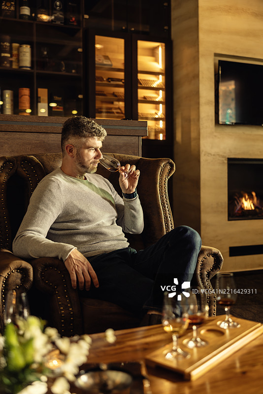 成年男子在时尚酒吧享受朗姆酒、干邑或威士忌图片素材