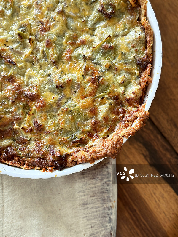 新鲜出炉的朝鲜蓟蓝纹奶酪咸派，俯视木桌上的美食图片素材