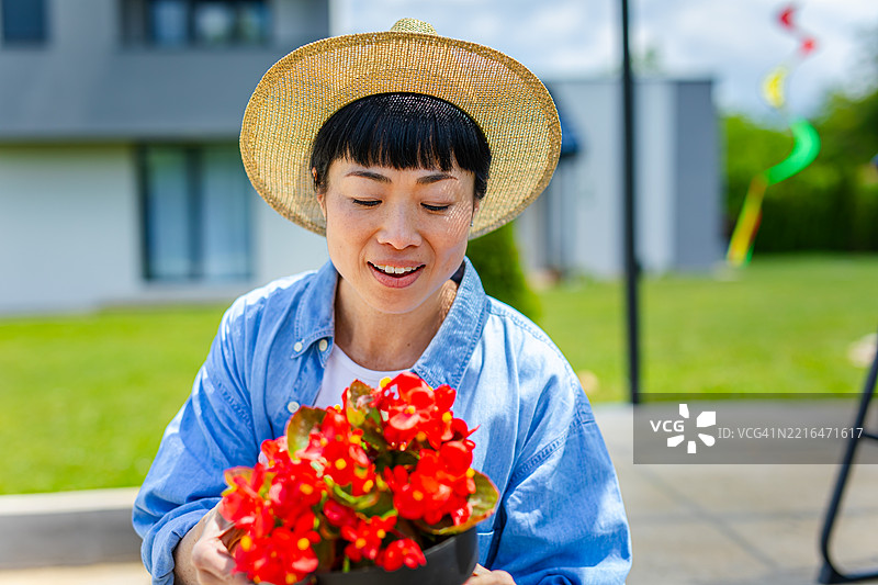 日本女性在院子里欣赏她的盆栽花卉图片素材
