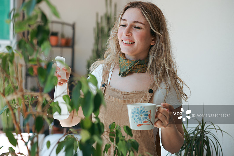 成年女性用白色喷雾瓶给室内植物喷水图片素材