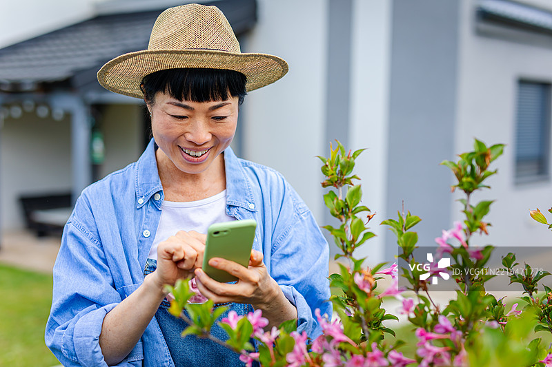 日本女性用手机检查她的花朵图片素材