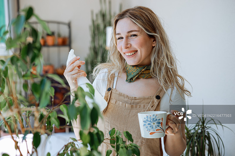 成年女性用白色喷雾瓶给室内植物喷水图片素材